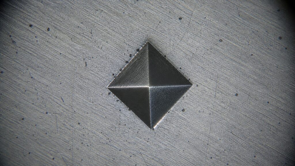 Vickers hardness test square indentation under microscope on polished metal surface